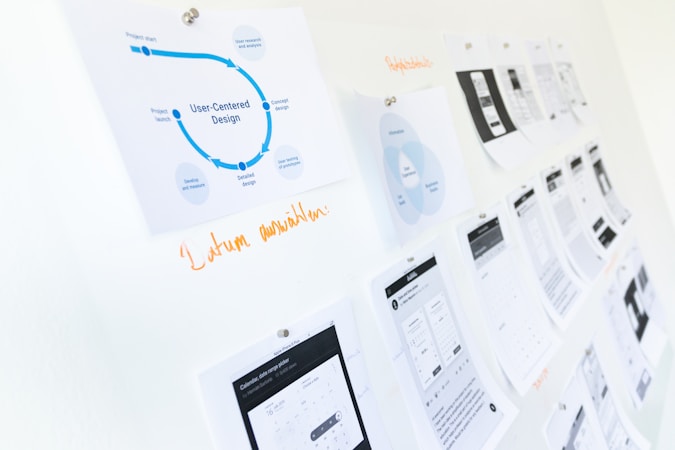 printouts on studio wall outlining design strategy - words "user-centered design" in foreground image - rest blurred