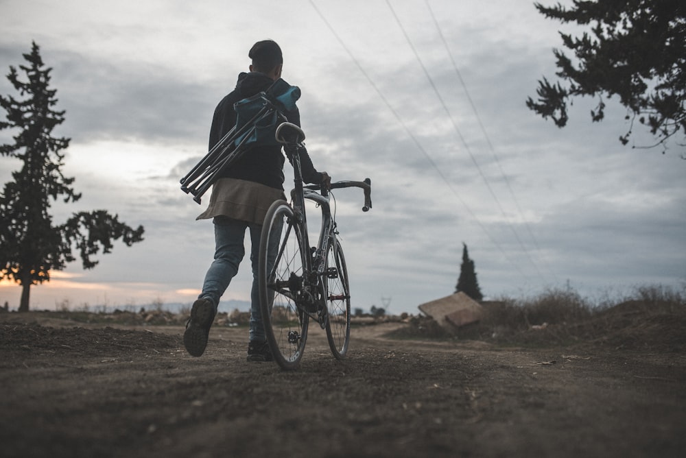 man walking beside road bike