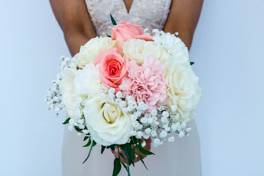 mujer con vestido de novia blanco sin mangas sosteniendo ramo de flores