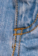Close-up of a sewing machine stitching premium denim with western-style patterns.