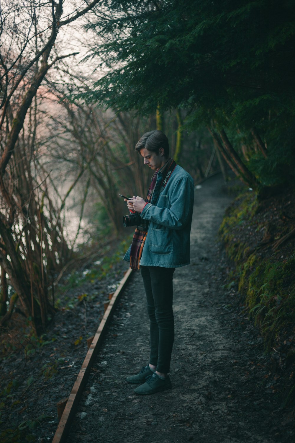 a man standing on a path looking at his cell phone