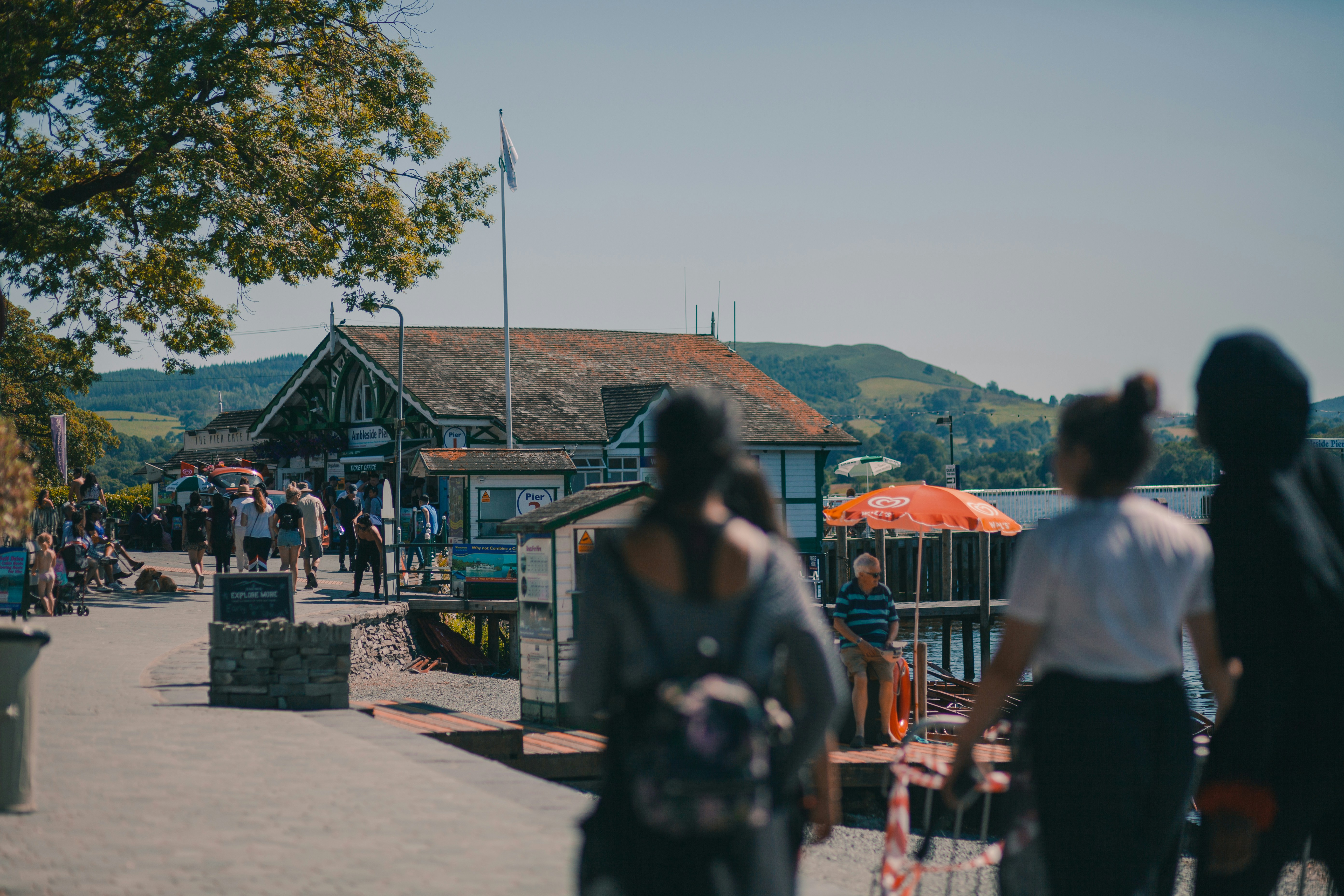 Un grupo de personas caminando por una acera junto a un cuerpo de agua