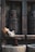 Three chickens are situated in a rustic setting. Two of them are perched on a wooden beam, and one is positioned in a stone trough. The setting features large, wooden mechanical components against a stone wall, giving a vintage and rural ambiance.