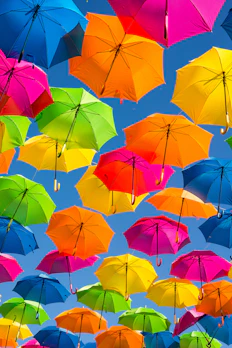 Many colorful umbrellas suspended against a clear blue sky
