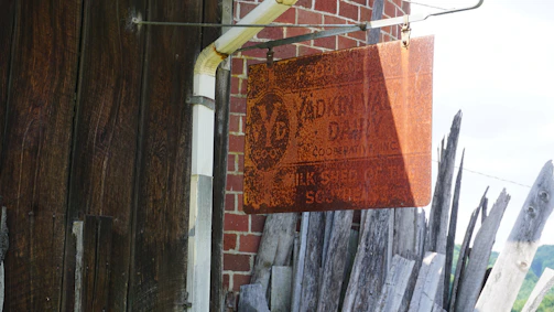 Rustic metal sign mounted on a textured brick wall.