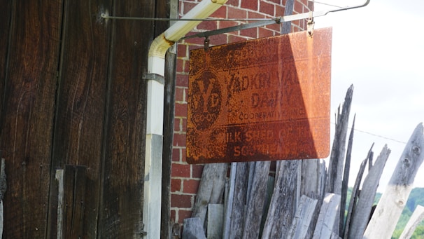 Rustic wooden sign with metal letters hanging on a brick wall.
