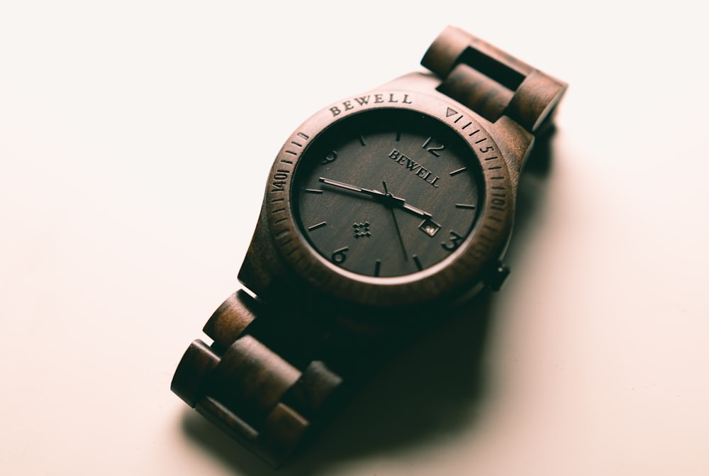 round gold-colored analog watch on white slab