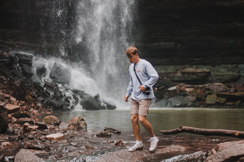 man standing beside river and waterfalls