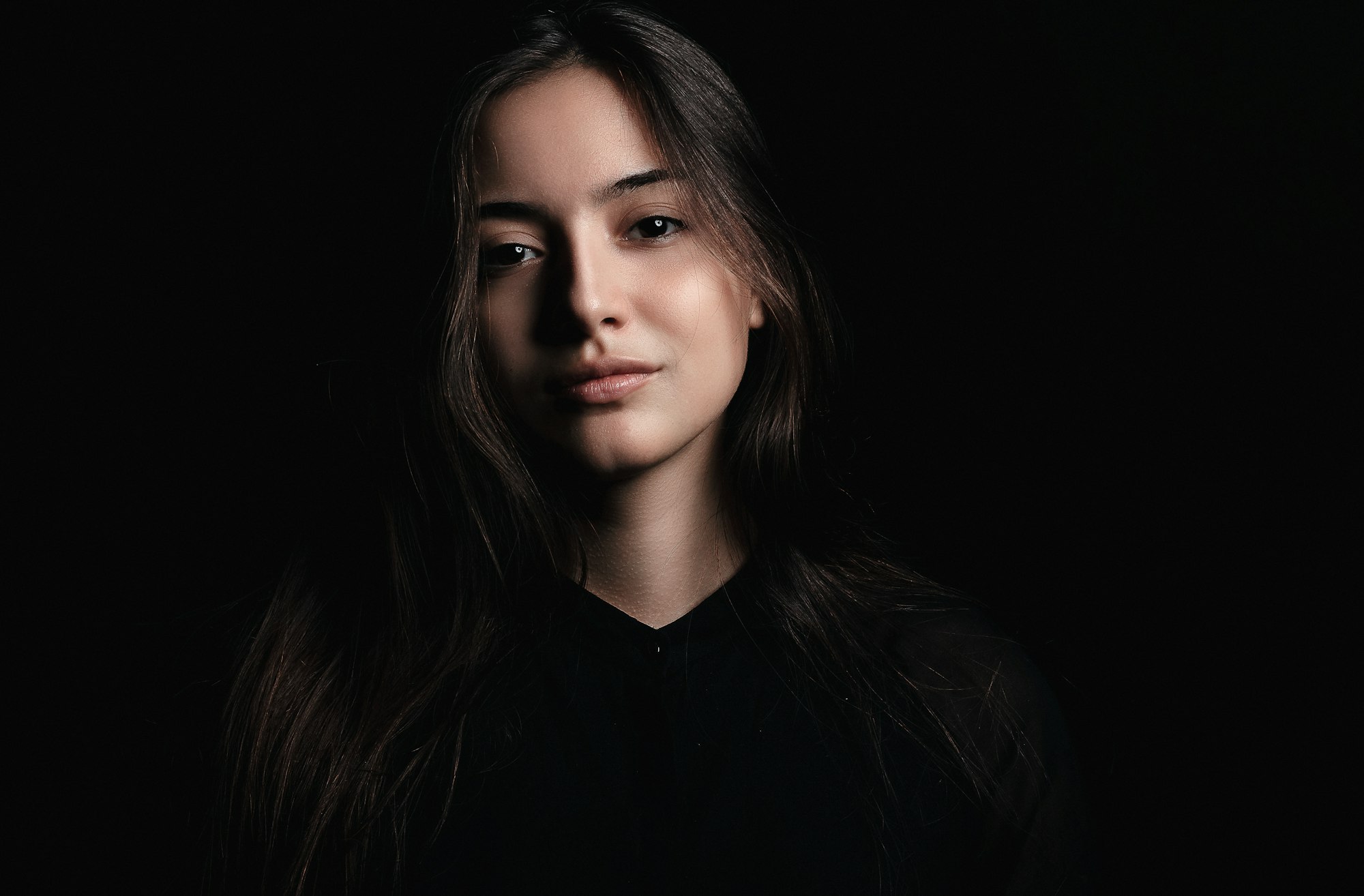 Portrait of a woman in a plain dark top against a soft grey wall