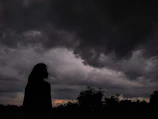 A silhouette of a person standing strong against a stormy sky, symbolizing resilience.