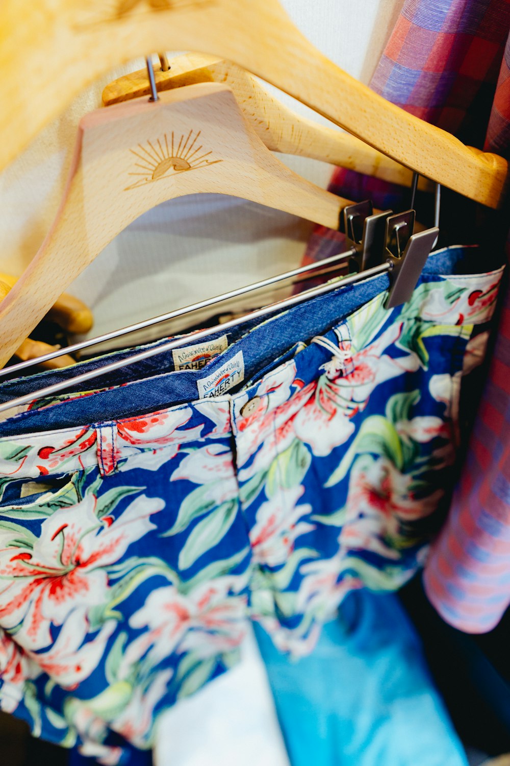 person holding blue and pink floral shorts