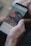 A hand is holding a smartphone displaying a social media app with a photo of a mountainous landscape.