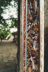Close-up of intricate Javanese wood carvings in dark green and gold hues.