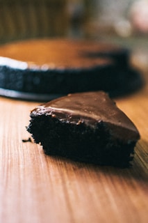 Close-up of a rustic chocolate cake with a glossy ganache finish on a wooden table