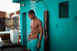 man in teal drawstring shorts taking a shower