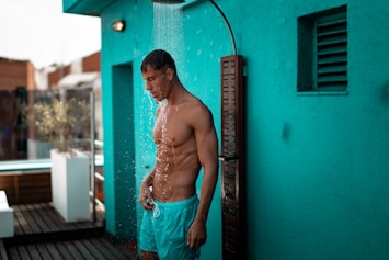 man in teal drawstring shorts taking a shower