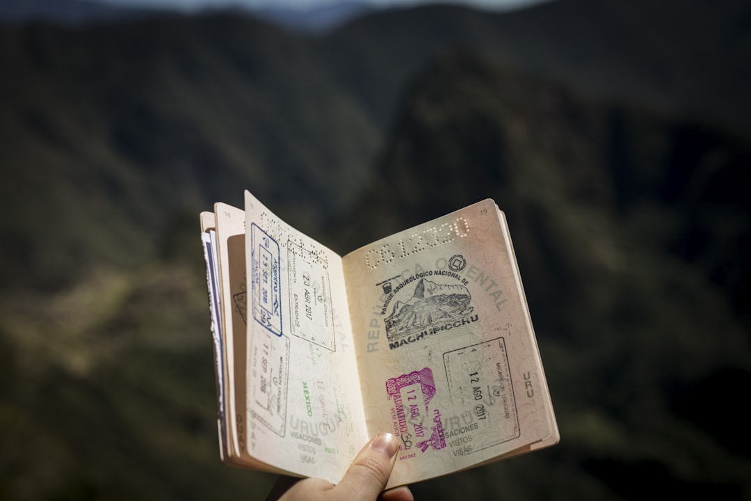 An open passport filled with entry and exit stamps, held up by a traveller