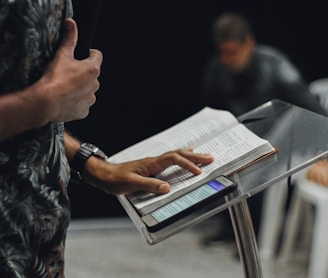 person standing while opening book on stage