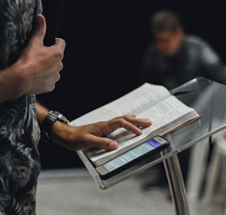 person standing while opening book on stage