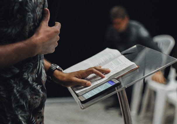 person standing while opening book on stage