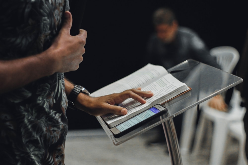 person standing while opening book on stage