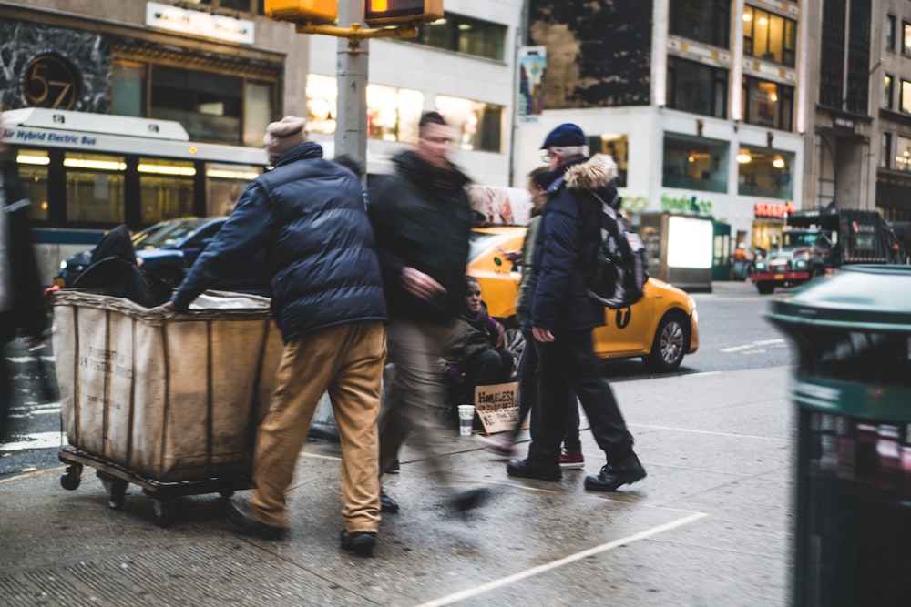 man walking on street beside man pushing cart