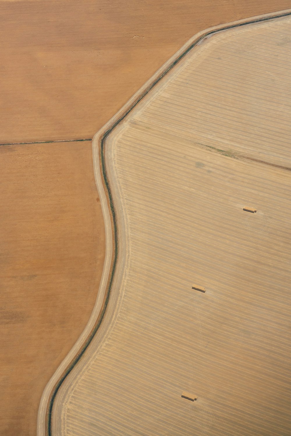 an aerial view of a field with a plane in the sky