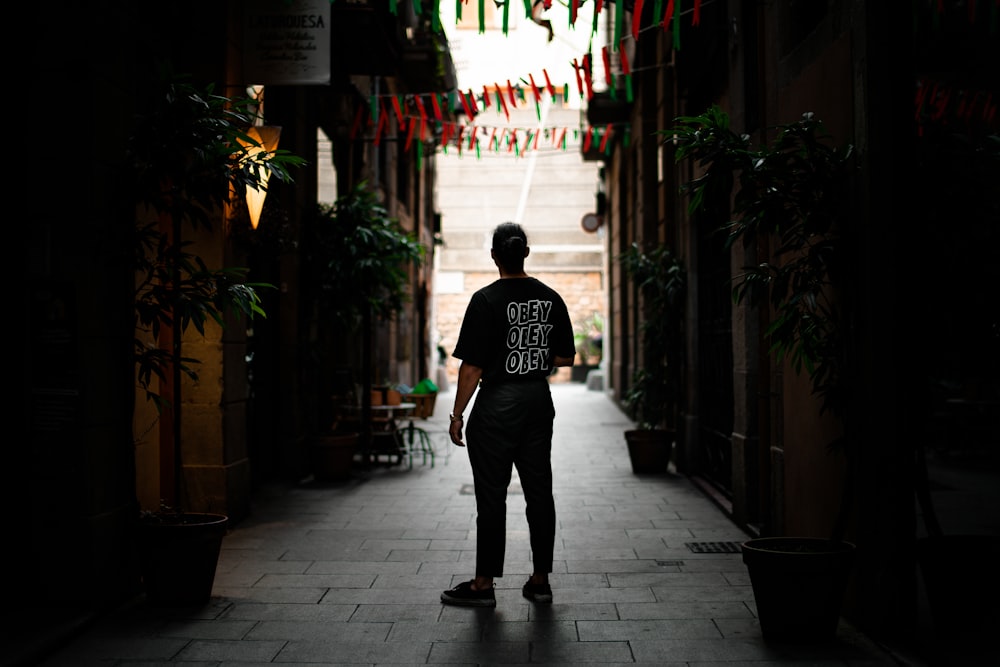 man standing in alley between buildings