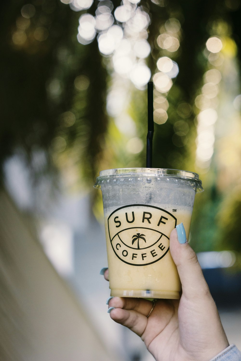 selective focus photography of person holding Surf coffee disposable cup