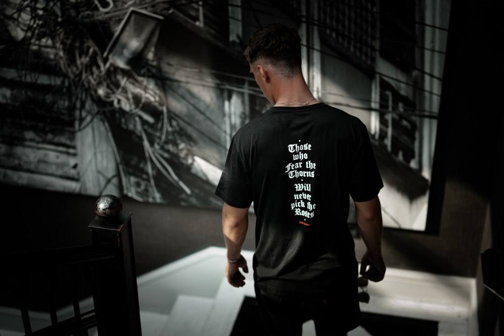 man in black crew-neck T-shirt looking down on white stair