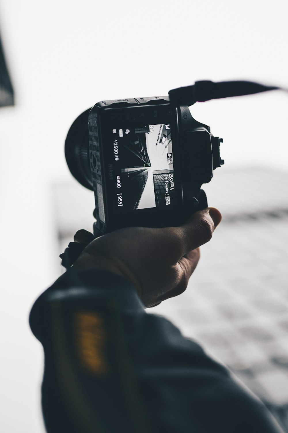 person taking low-angle photo of high-rise buildings using black DSLR camera during daytime