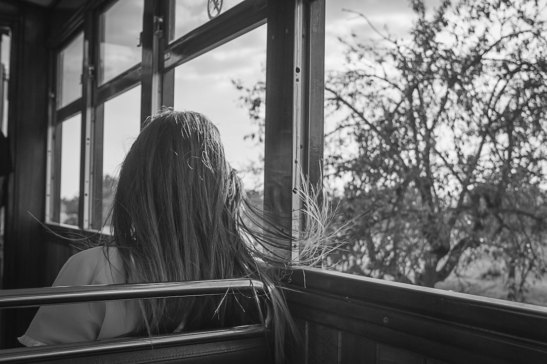 woman sitting beside window, Girl traveling on a cold train looking at the window