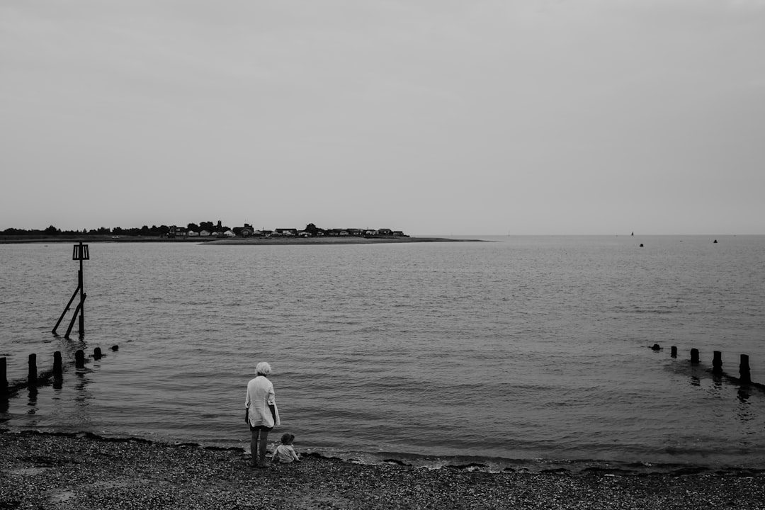 grayscale photo of woman and toddler near body of water