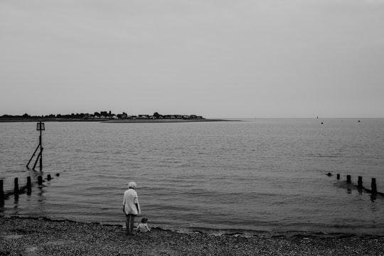 grayscale photo of woman and toddler near body of water in Brightlingsea United Kingdom
