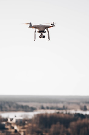 A modern drone flying over a large landscape for aerial mapping and surveying.
