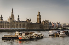 four white boats traveling on river beside Big Ben in London