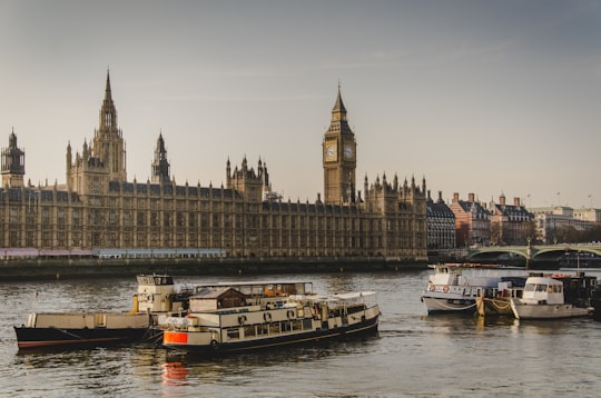 four white boats traveling on river beside Big Ben in London in Houses of Parliament United Kingdom