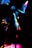 A dynamic and colorful scene featuring a silhouetted figure dancing under vibrant lights. The image captures the movement and energy through streaks of neon pink, blue, and yellow against a dark background.