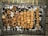 Several skewers of grilled meat are arranged over a bed of charcoal on a barbecue grill. The meat appears to be well-cooked with a slightly charred exterior.