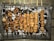 Several skewers of grilled meat are arranged over a bed of charcoal on a barbecue grill. The meat appears to be well-cooked with a slightly charred exterior.