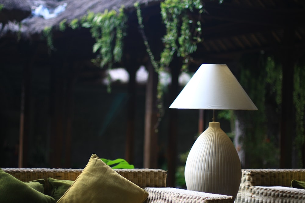 turned-off white table lamp near brown wicker chair