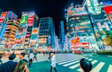 people crossing pedestrian near buildings at night