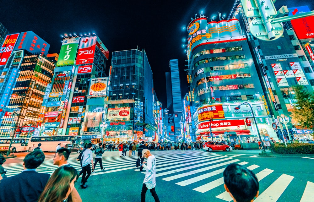 people crossing pedestrian near buildings at night