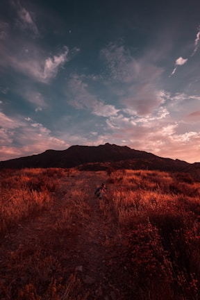 Sunset over a mountain trail, with a hiker sporting a fannypack from our collection.