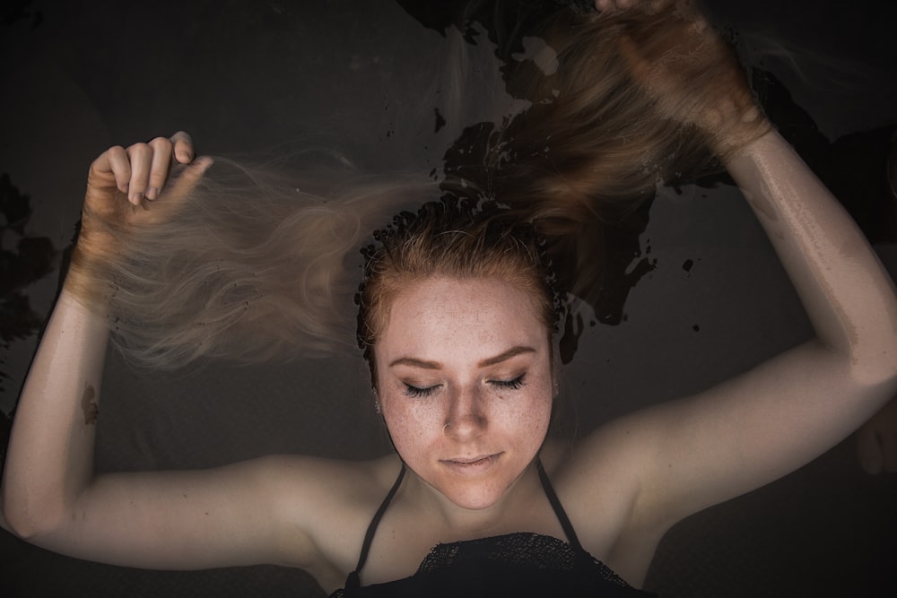 woman lying above water closing her eyes