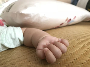 Close-up of tiny baby hands resting peacefully on a plush beige pillow