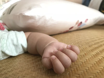 Close-up of a baby’s hands exploring a textured sensory toy in bright colors.