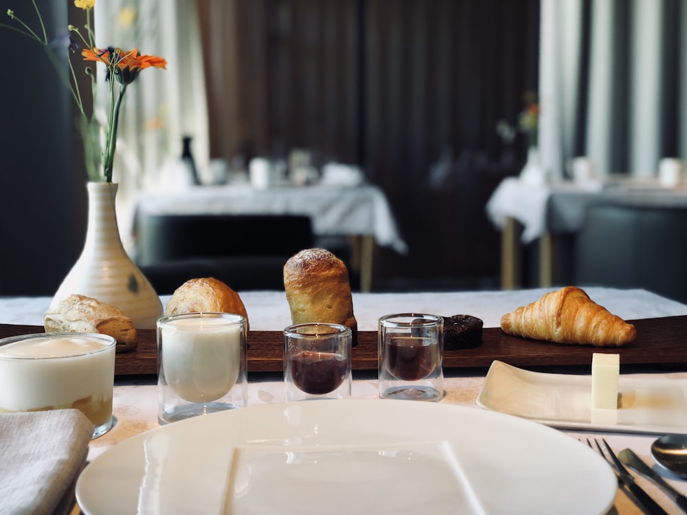 four baked breads on brown wooden table beside shot glasses