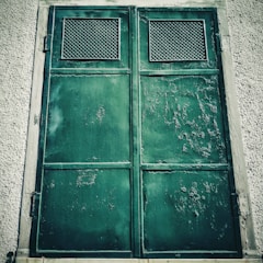 Workers installing a large steel door at an industrial site.