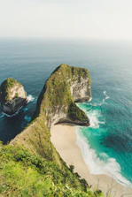rock formation beside ocean under white clouds during daytime